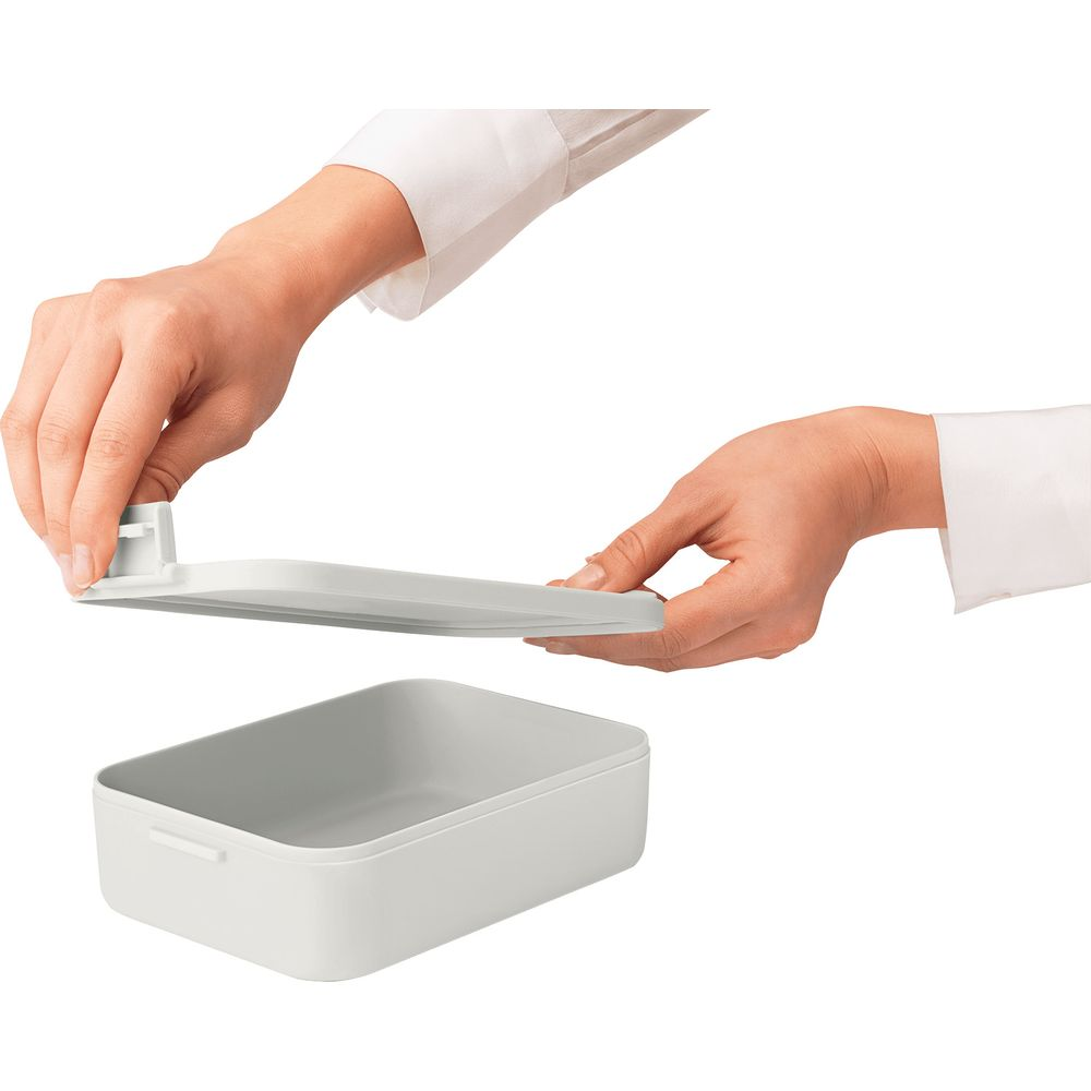 Contenitore grigio con coperchio tenuto dalle mani.