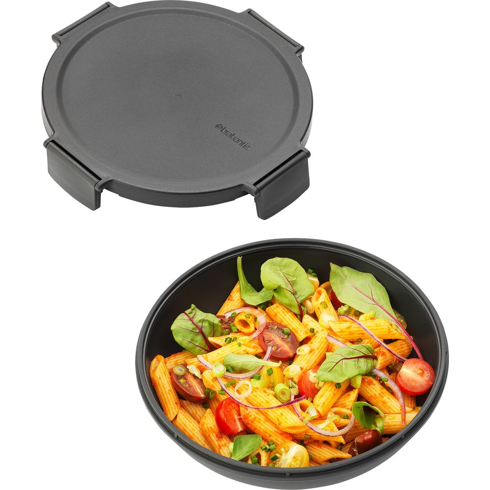 Coperchio grigio sopra una ciotola di pasta penne, pomodori e verdure.