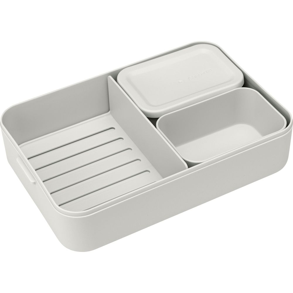 Un contenitore grigio con più scomparti, tra cui un piatto rettangolare e un piatto oblungo con coperchio.