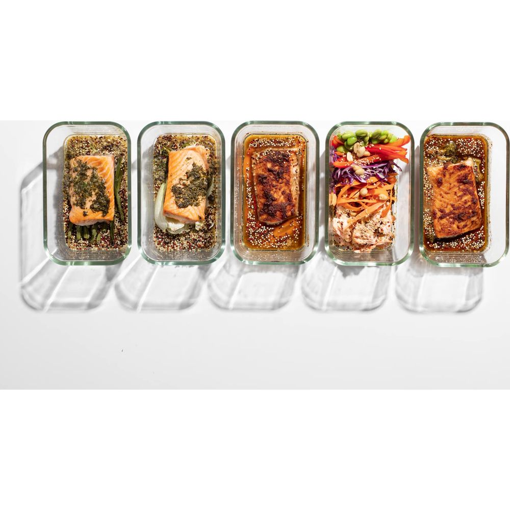 Cinque contenitori di vetro per pasti: salmone su quinoa e verdure, salmone, salmone con insalata, salmone.