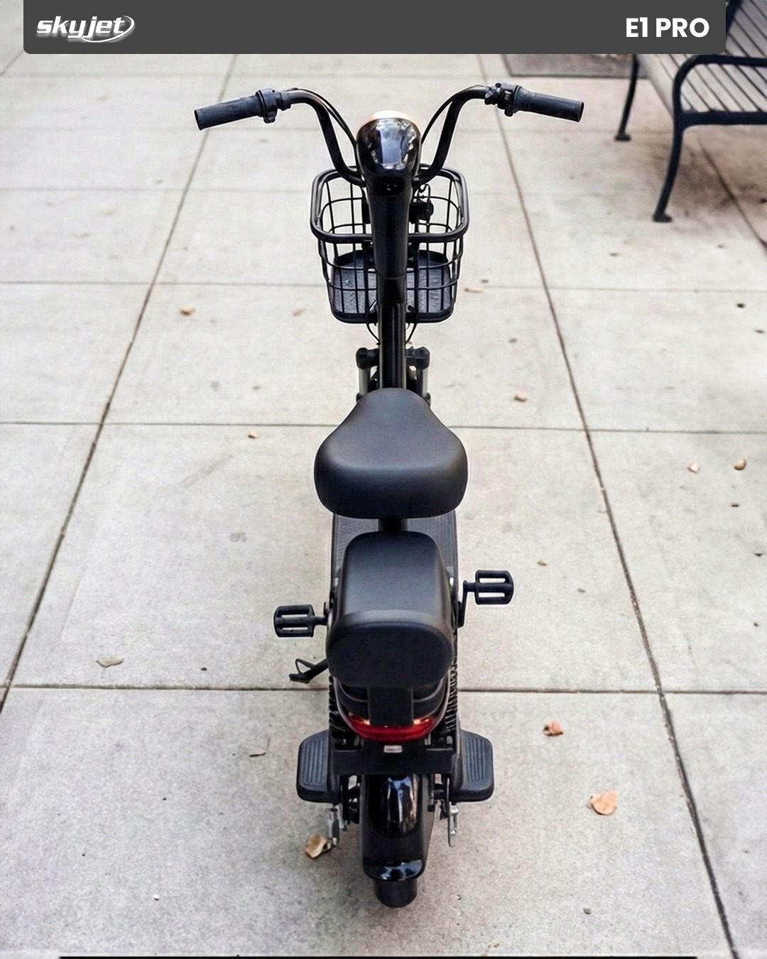 Sepetli, oturaklı ve pedallı siyah elektrikli scooter, Arnavut kaldırımlı yolda.