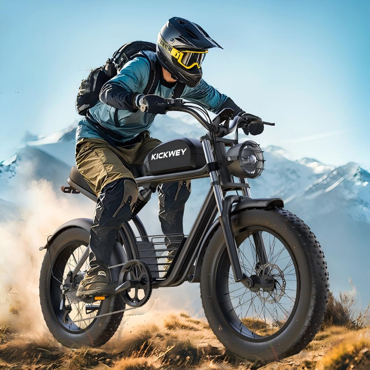 Kolarz w odzieży ochronnej na rowerze elektrycznym w górzystym terenie pod błękitnym niebem.