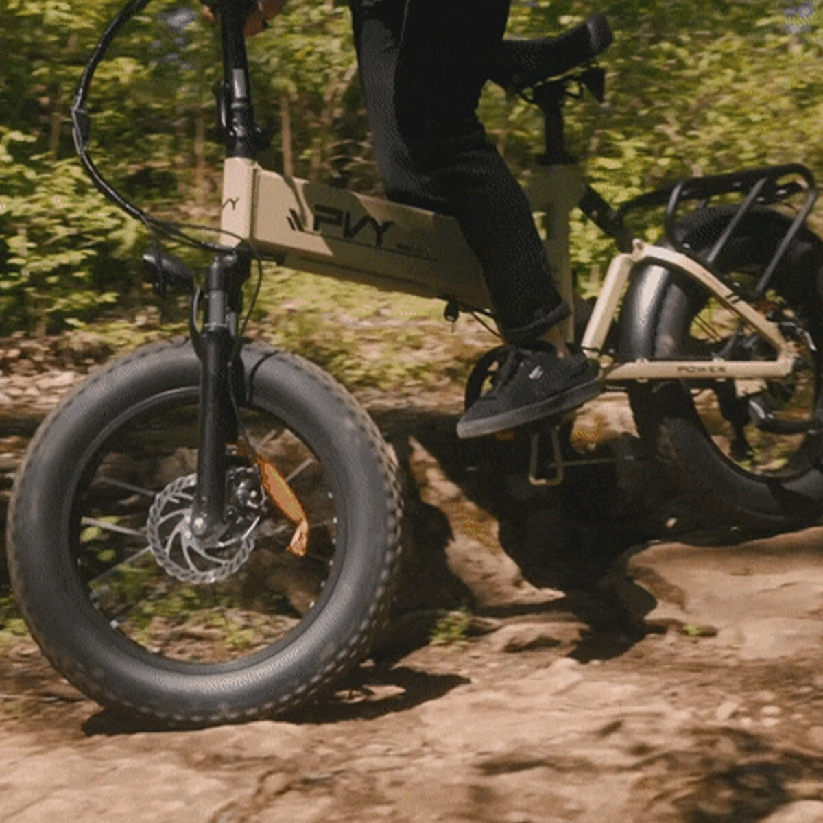 Osoba jedzie na piaskowym rowerze elektrycznym z grubymi oponami po lesie.