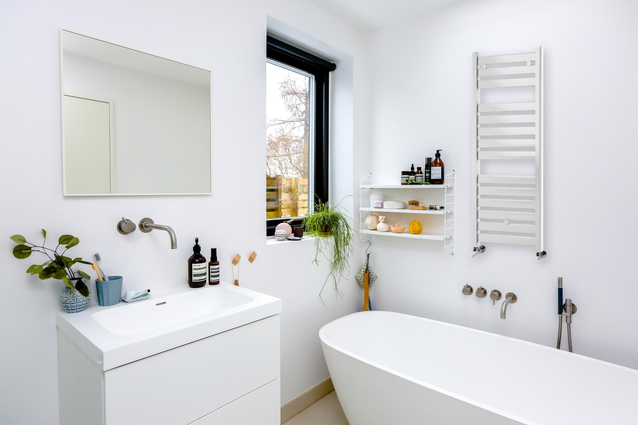 Baño moderno con bañera exenta, lavabo, espejo y toallero.