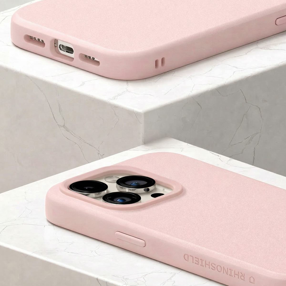 Twee roze telefoonhoesjes met cameralensmodules op marmeren treden.