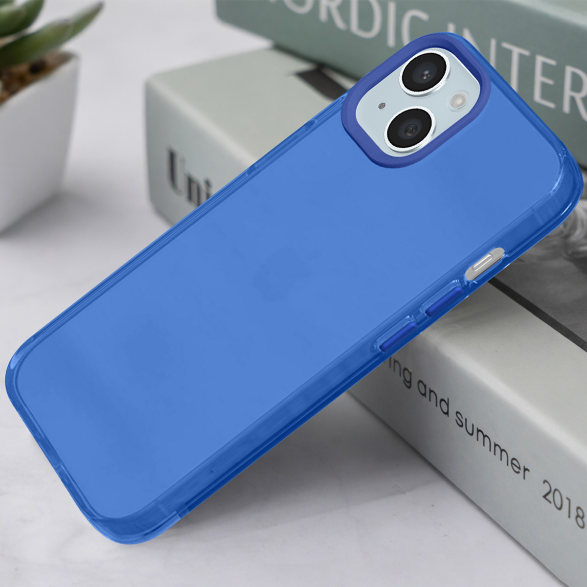 Une coque bleue pour iPhone repose sur des livres. Deux caméras à l'arrière.