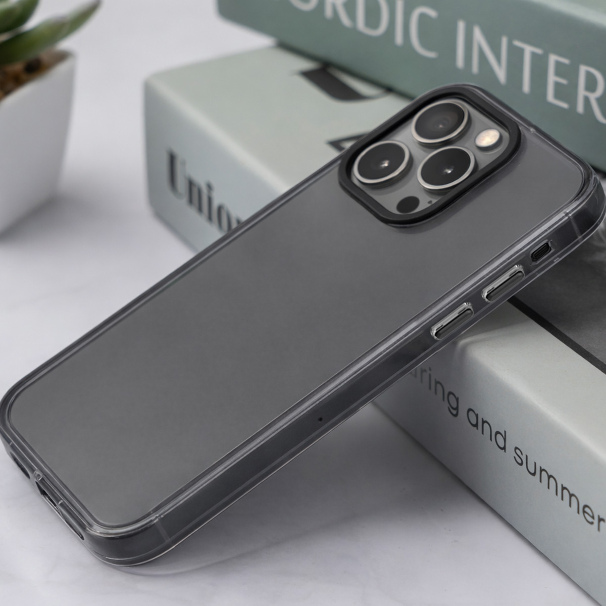 Custodia grigia per telefono con tre fotocamere su una pila di libri.