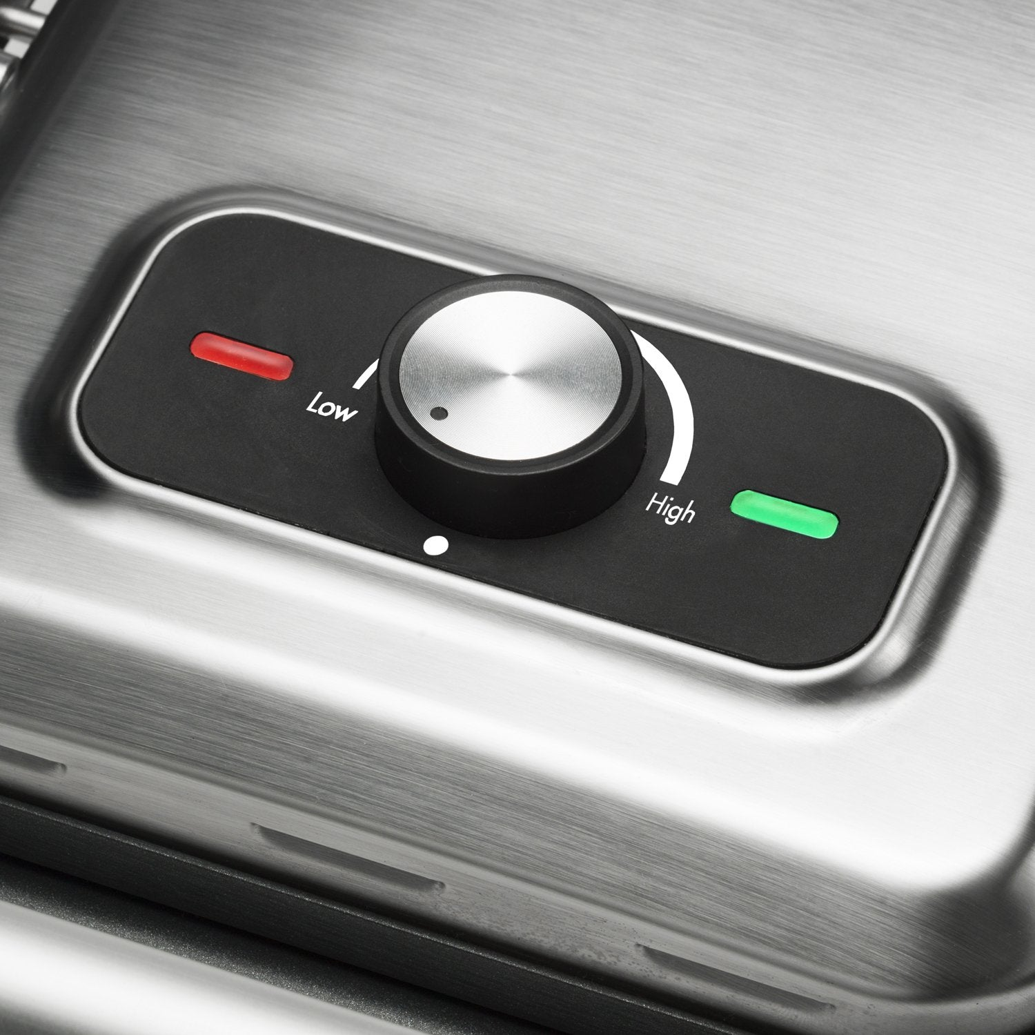 Close-up of a brushed metal appliance with a black control panel. A silver dial is set between 'Low' (red indicator) and 'High' (green indicator).