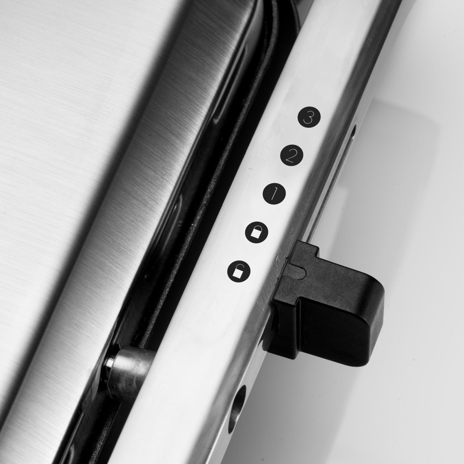 Close-up of a silver surface with black markings 1, 2, 3 and a black latch.
