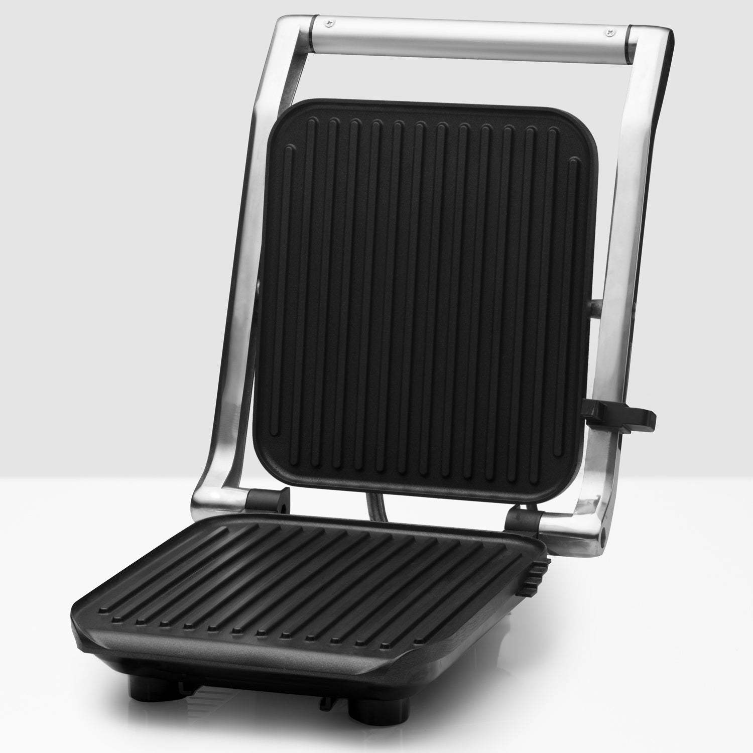 An open contact grill with black ribbed plates and a silver frame.