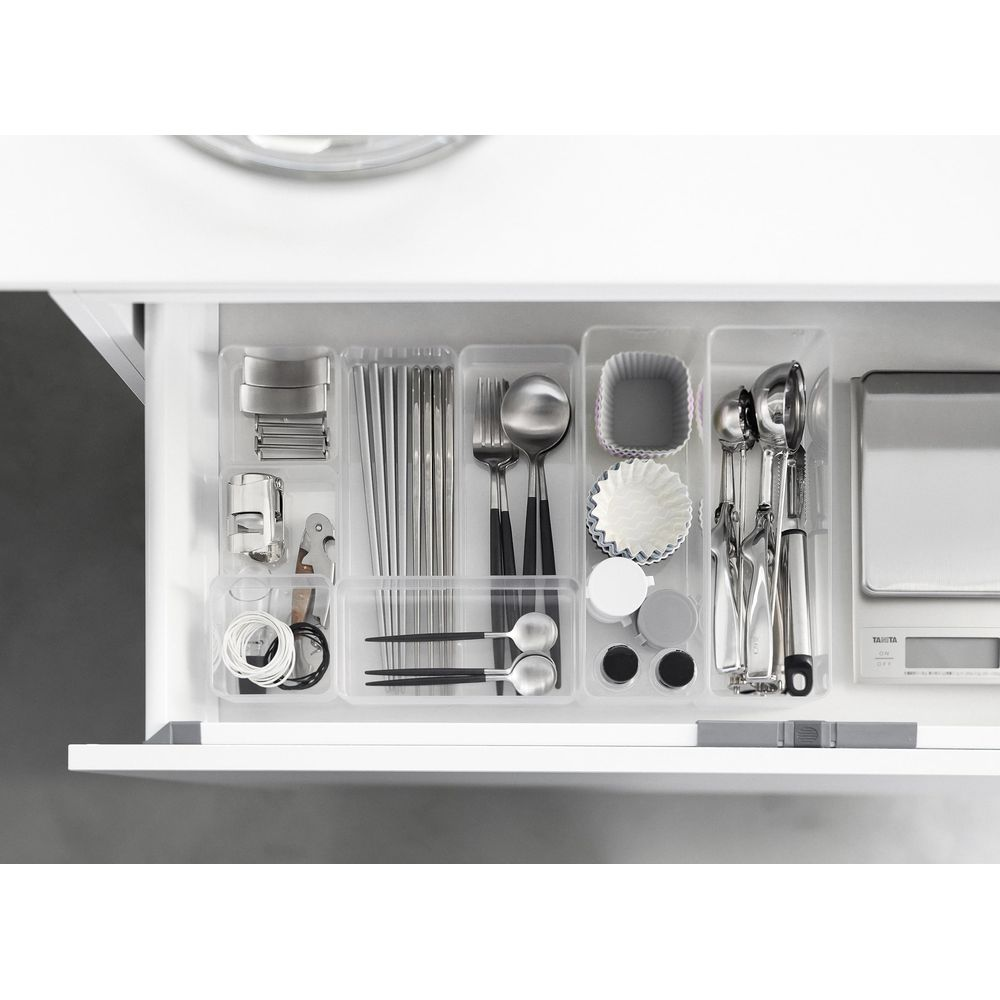 Cassetto da cucina con vari utensili organizzati in contenitori trasparenti.