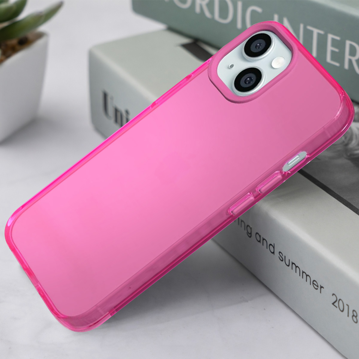 Een felroze telefoonhoesje ligt op boeken. De camera's zijn zichtbaar.