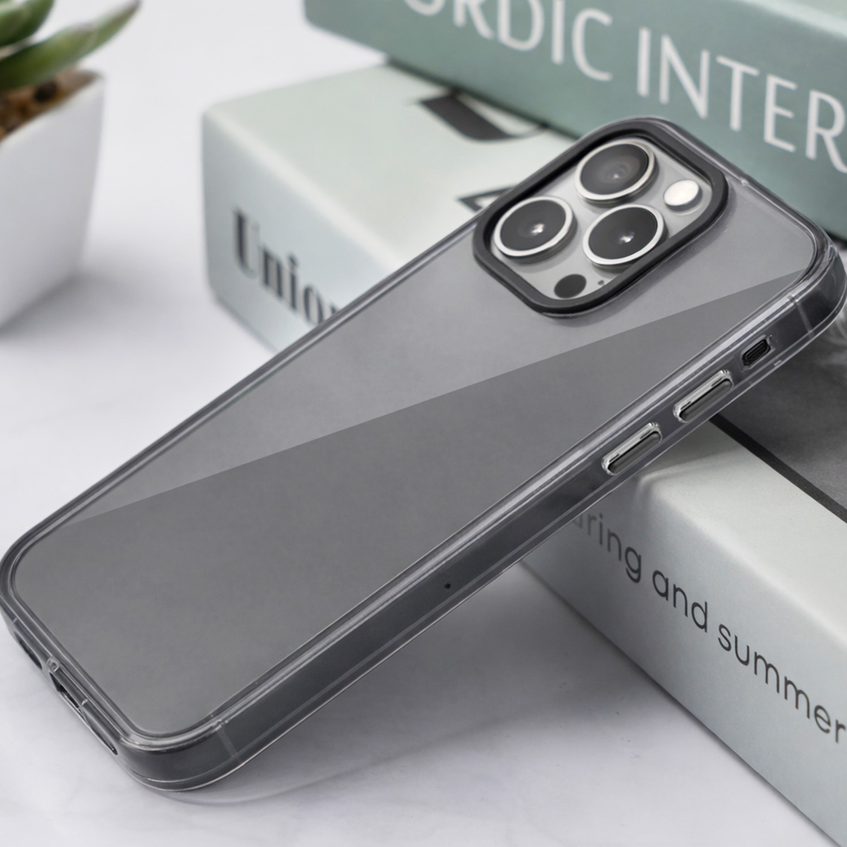 Une coque de téléphone transparente à bord noir repose sur des livres.