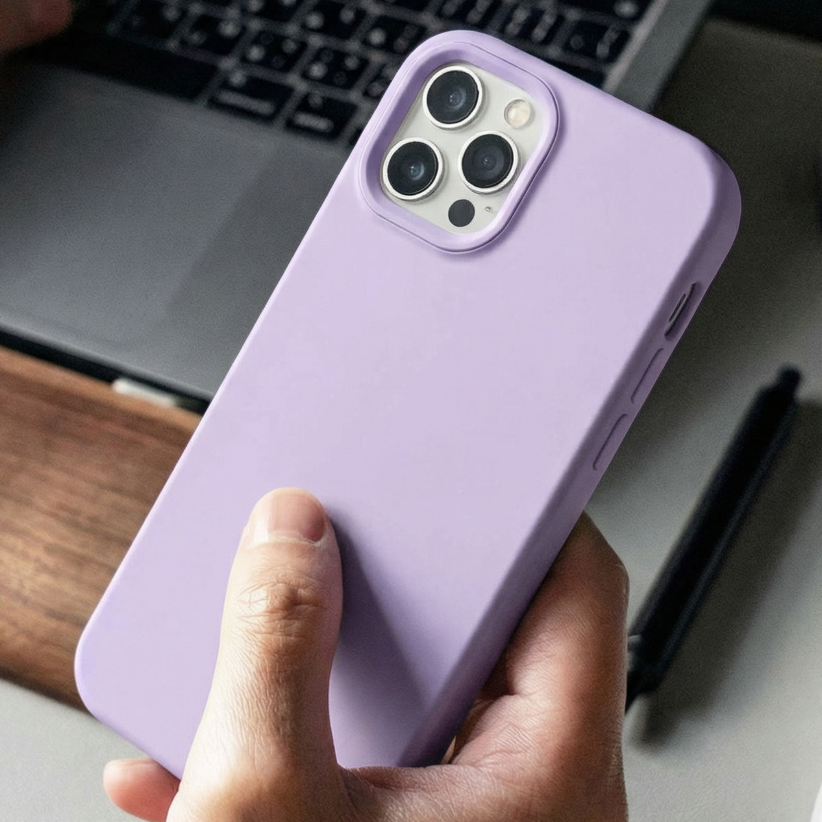 Une main tient un téléphone violet avec trois objectifs de caméra.