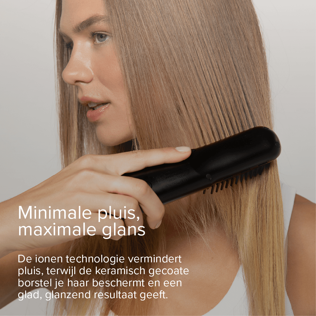 A woman is straightening her blonde hair with a black hair straightening brush.
