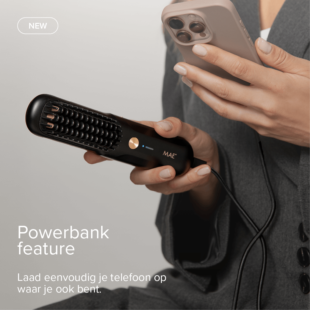 A black MAE device with a comb attachment is held, charging a beige phone.