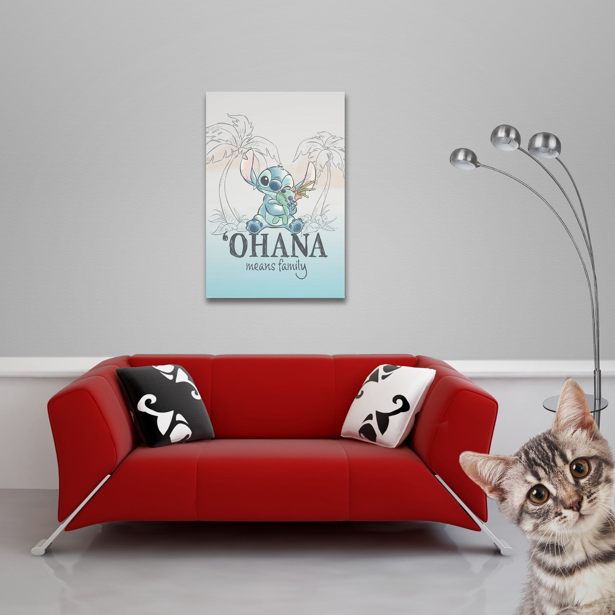 Ein rotes Sofa mit zwei Kissen steht vor einer Wand mit einem Stitch-Poster. Eine Katze lugt von rechts hervor.