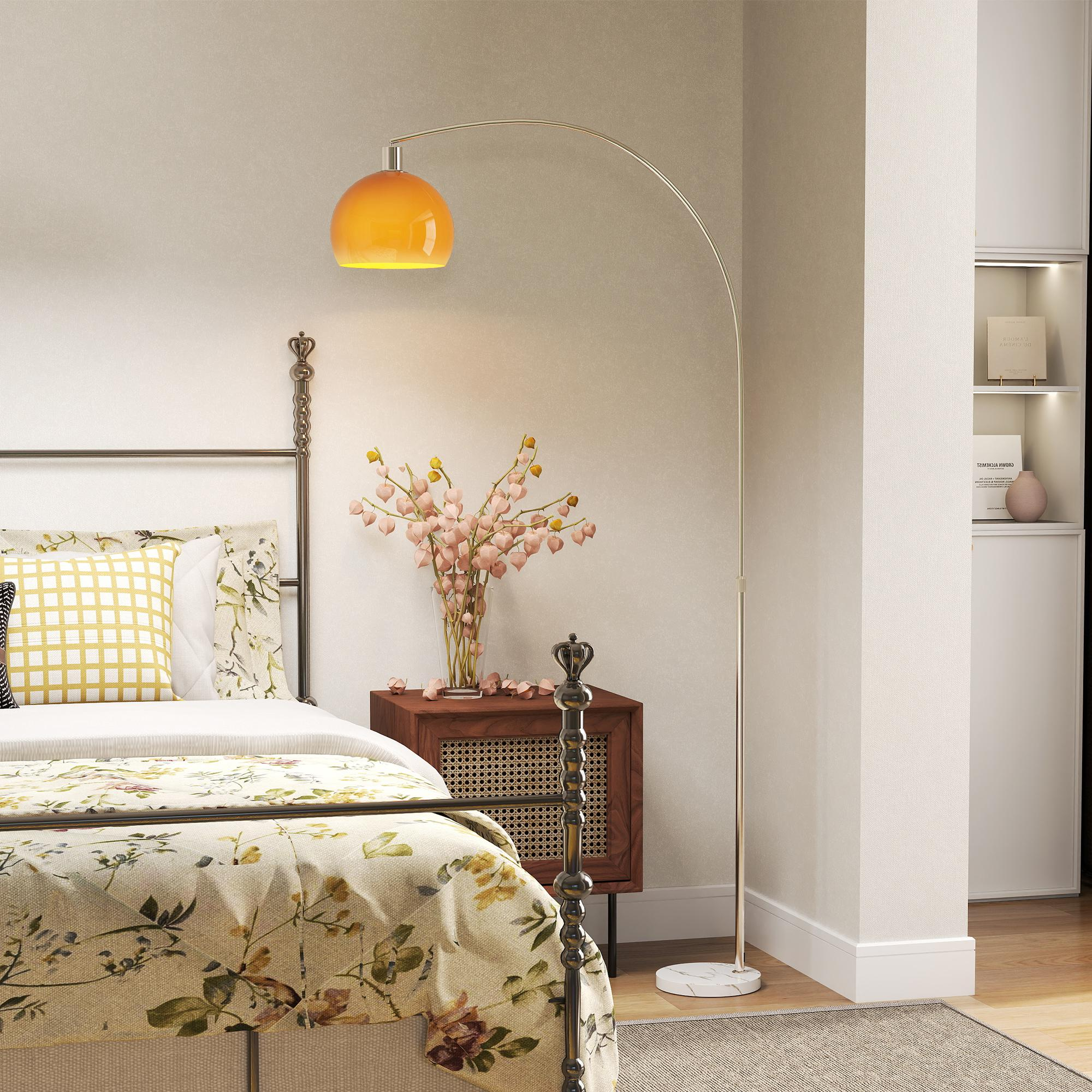 Una camera da letto con letto floreale, comodino e lampada ad arco.