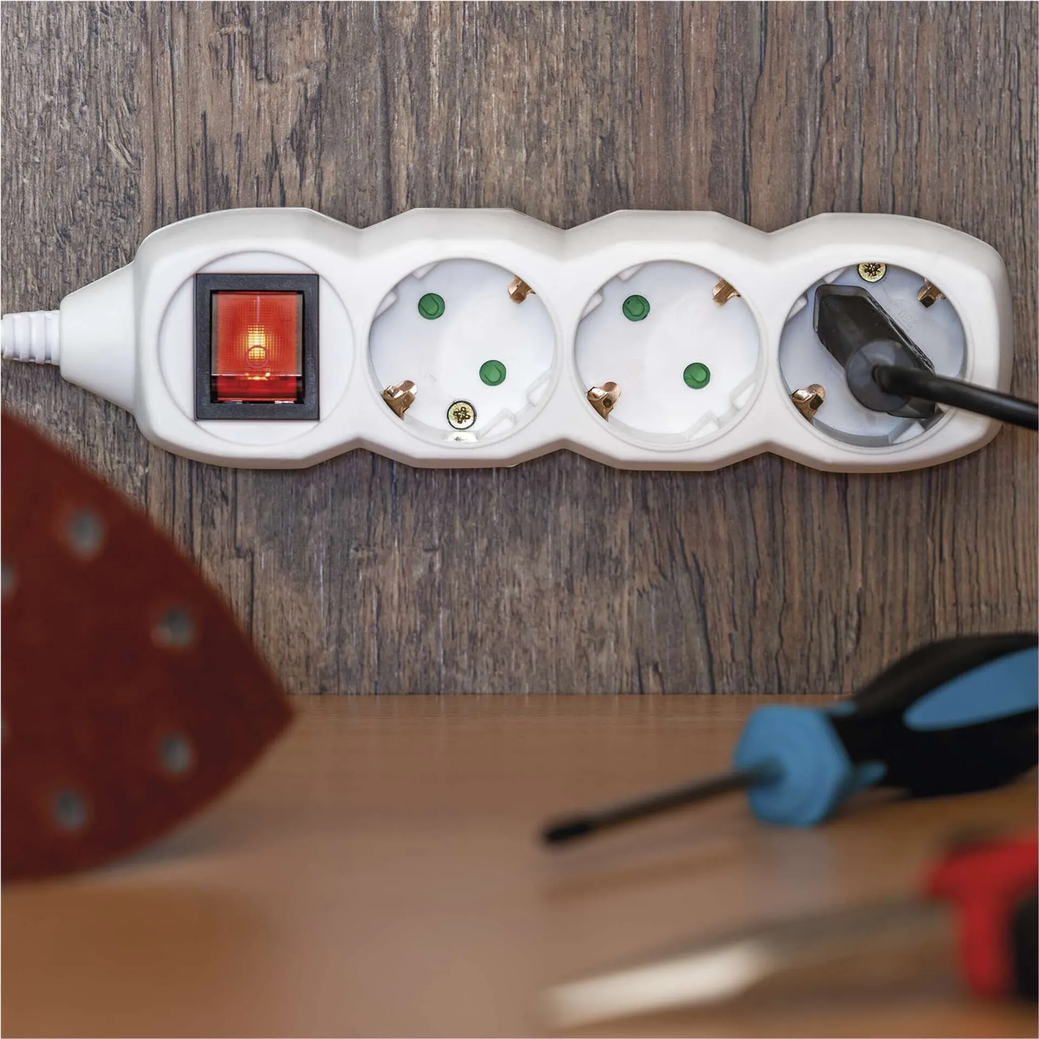 Ein weißer Mehrfachsteckdosenadapter mit rotem Schalter und eingestecktem Stecker.
