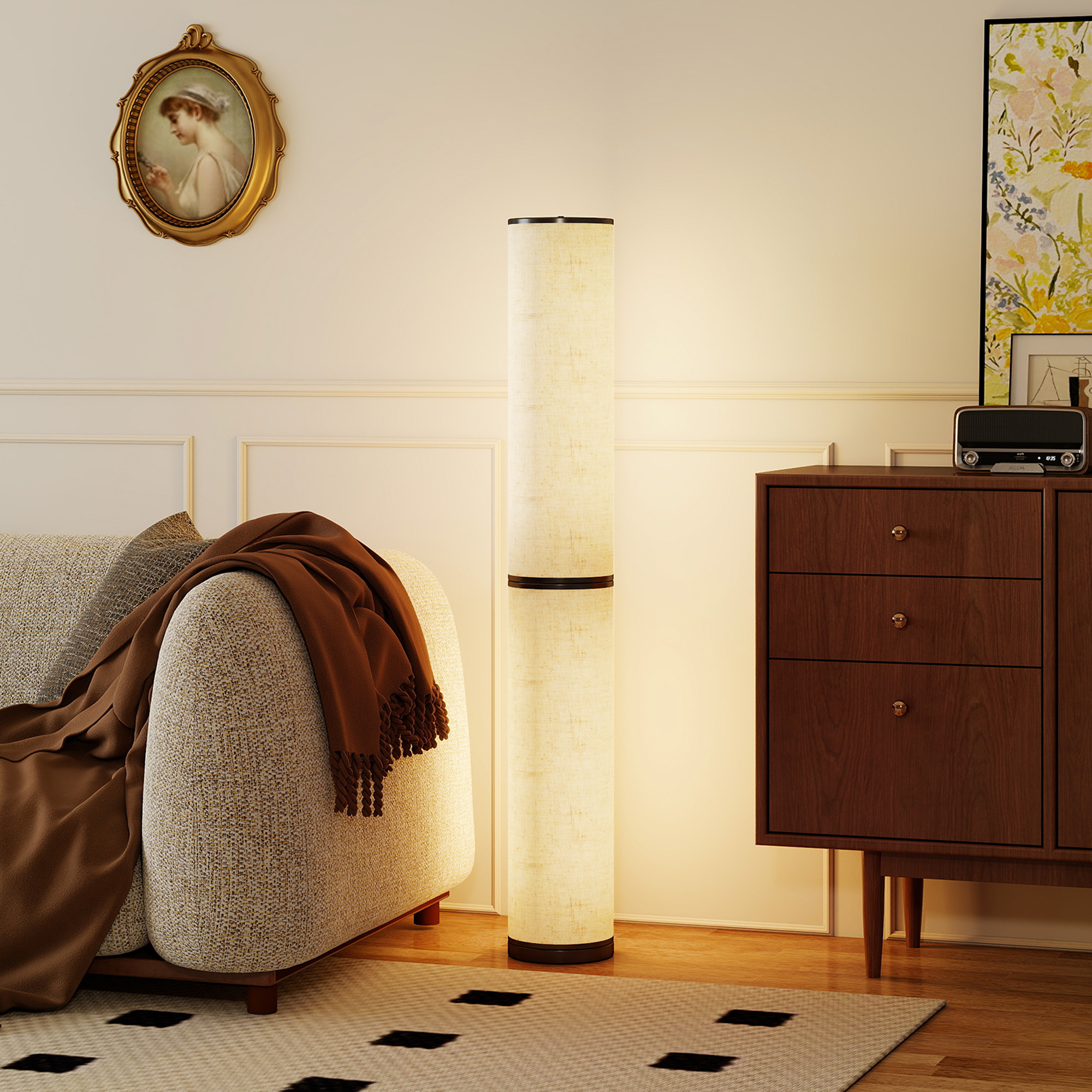 Un divano beige con plaid marrone, lampada da terra e cassettiera in legno con radio.