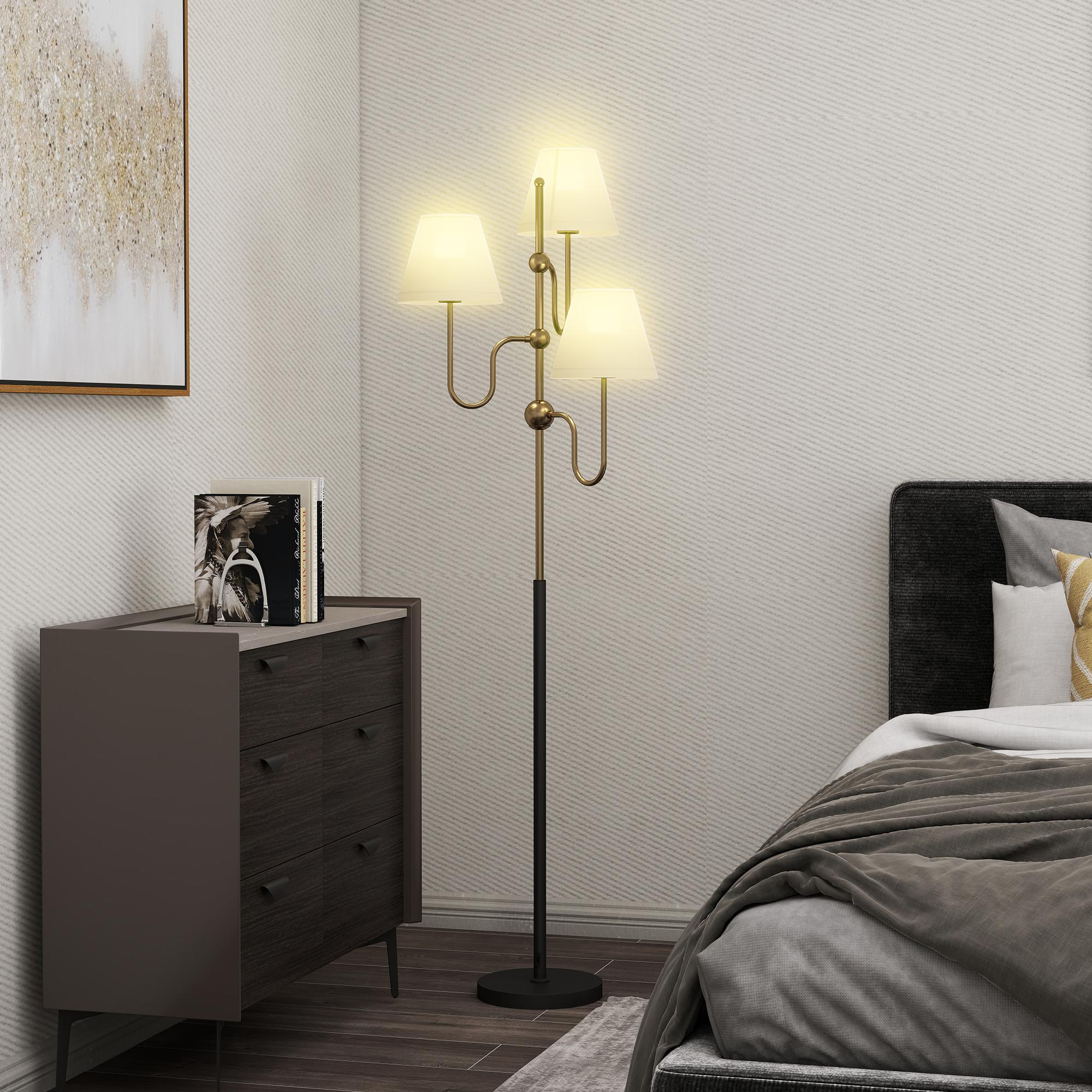 Una camera da letto con comodino, lampada da terra a tre luci e letto.