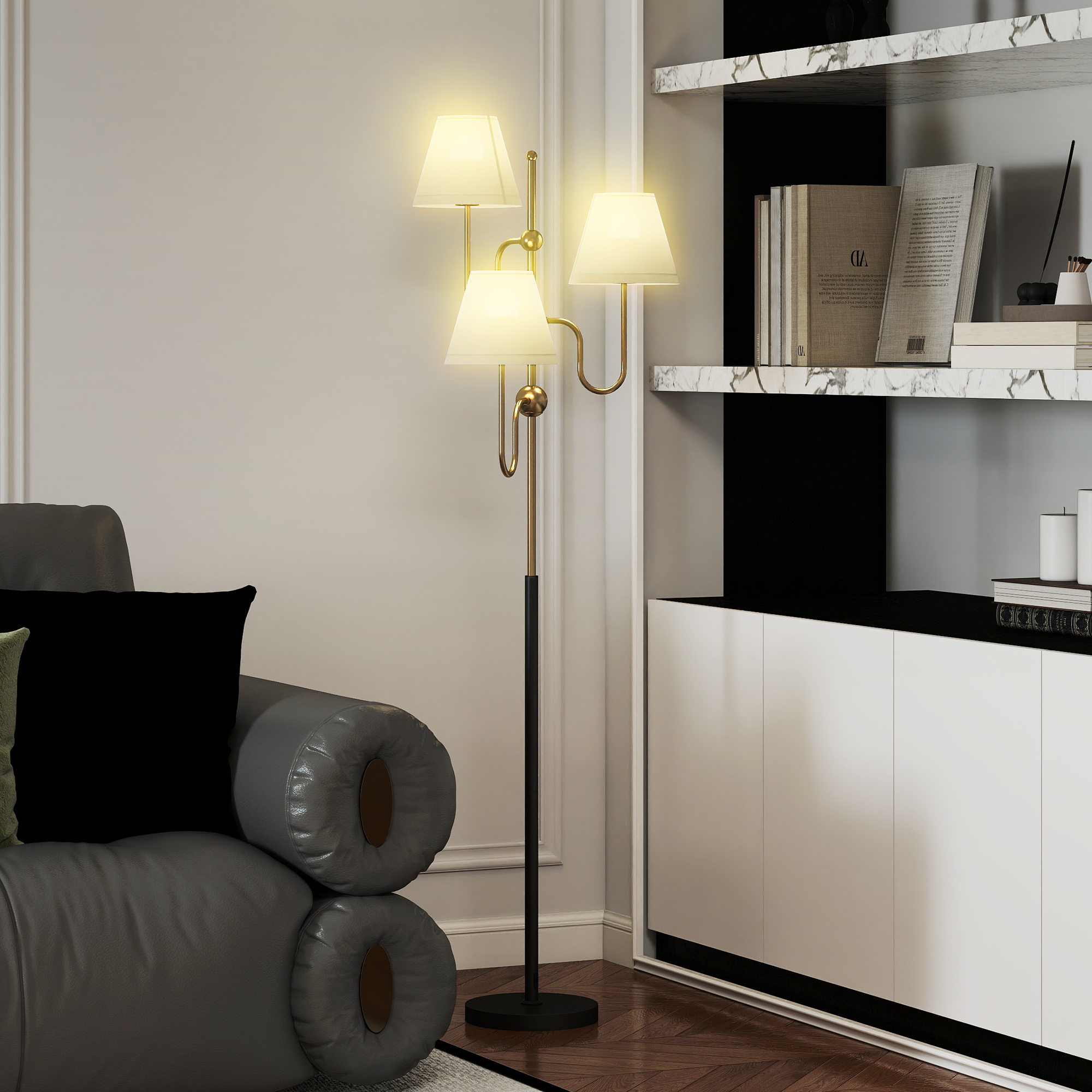 Lampada da terra dorata a tre teste accanto a un divano grigio con cuscini neri.