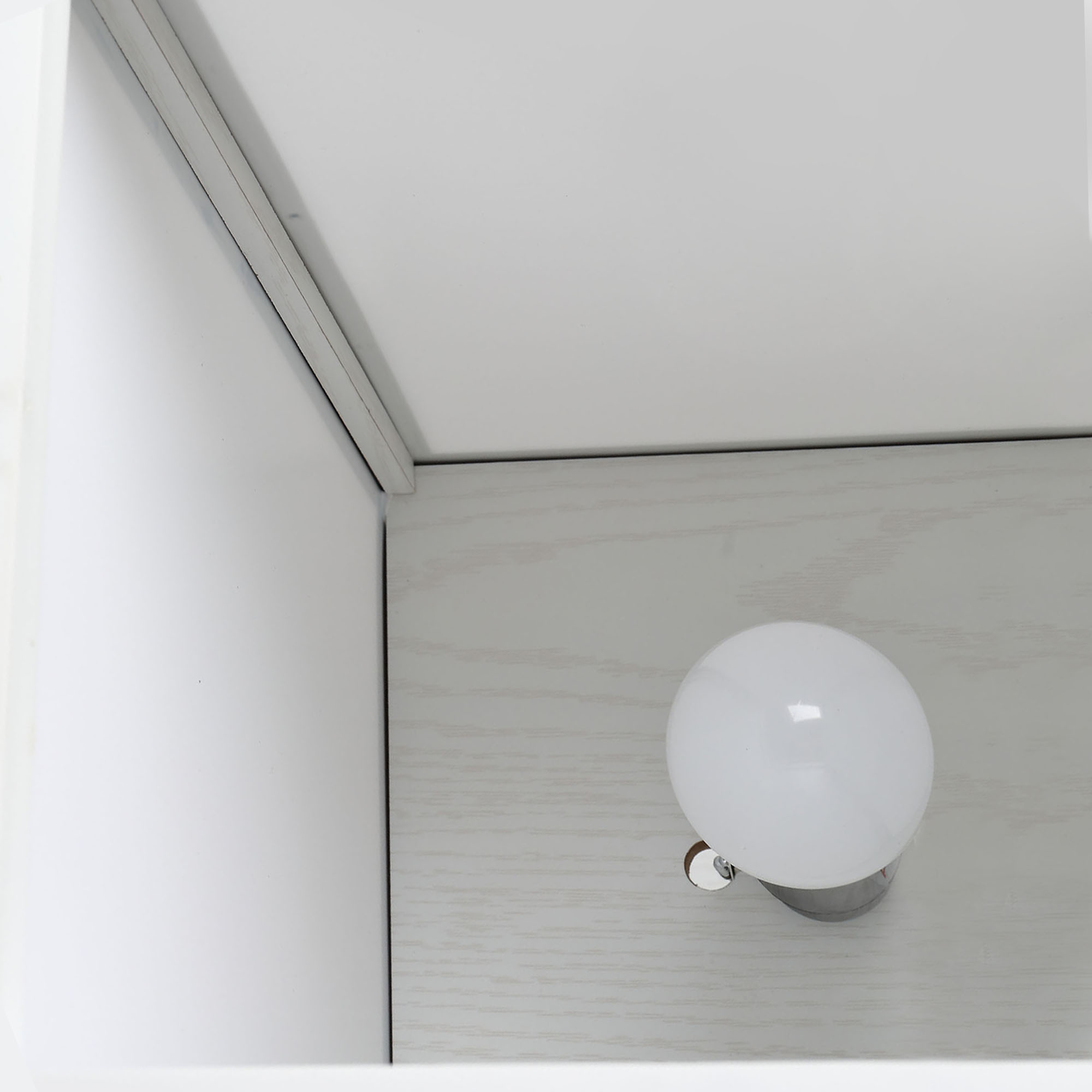 Una lampadina bianca in un portalampada grigio su una superficie di legno chiaro.