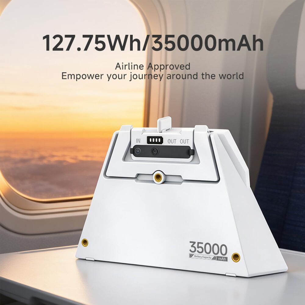 Ein weißer Powerbank auf einem Flugzeugtisch mit Sonnenuntergang draußen.