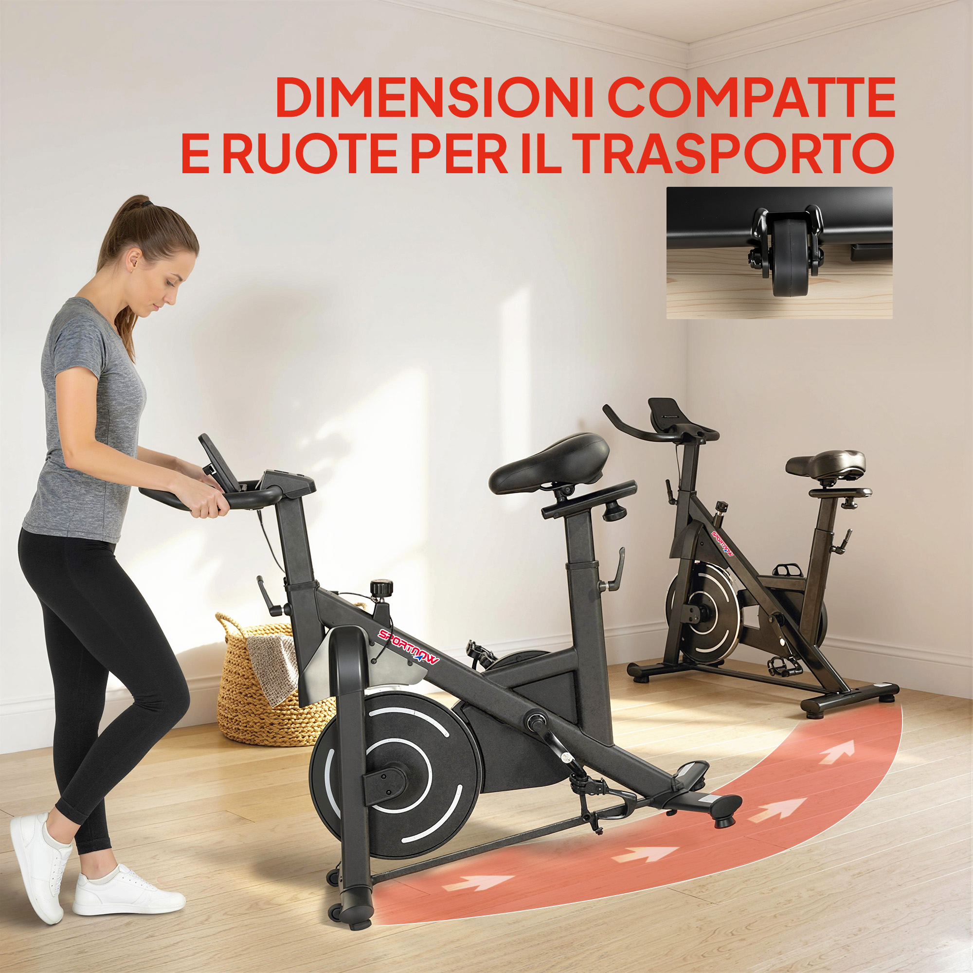 Una donna si allena su una cyclette in una stanza con pavimento in legno. Una seconda bici sullo sfondo.