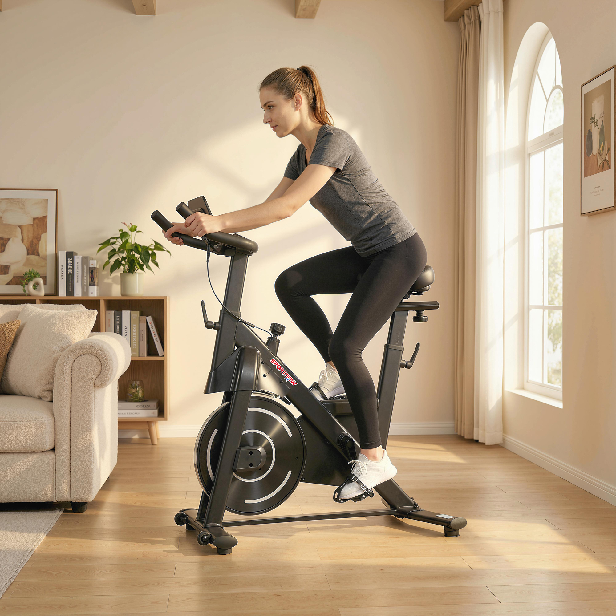 Una donna si allena su una cyclette nera in una stanza luminosa con divano.