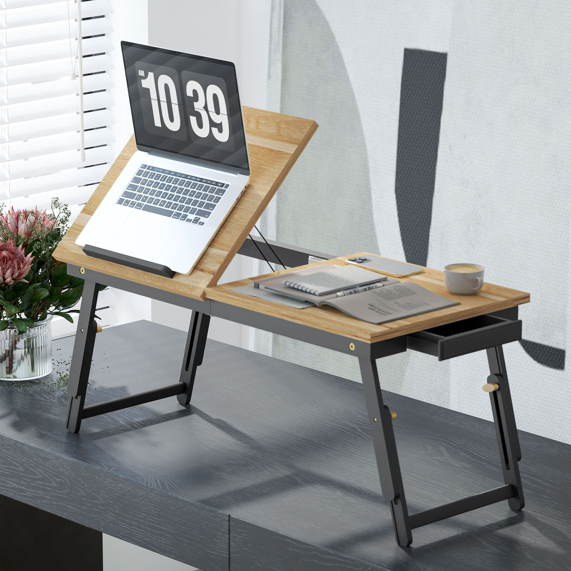 Un tavolino per laptop con laptop, libro, telefono e tazza di caffè.