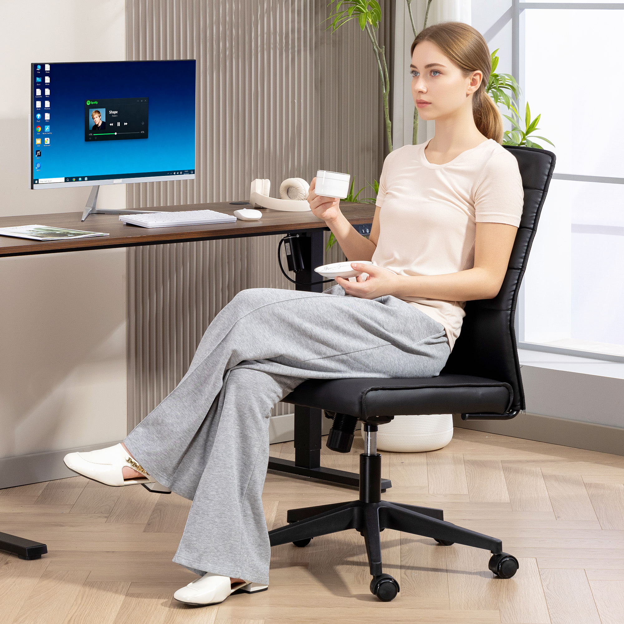 Una donna siede a una scrivania con un computer e cuffie.