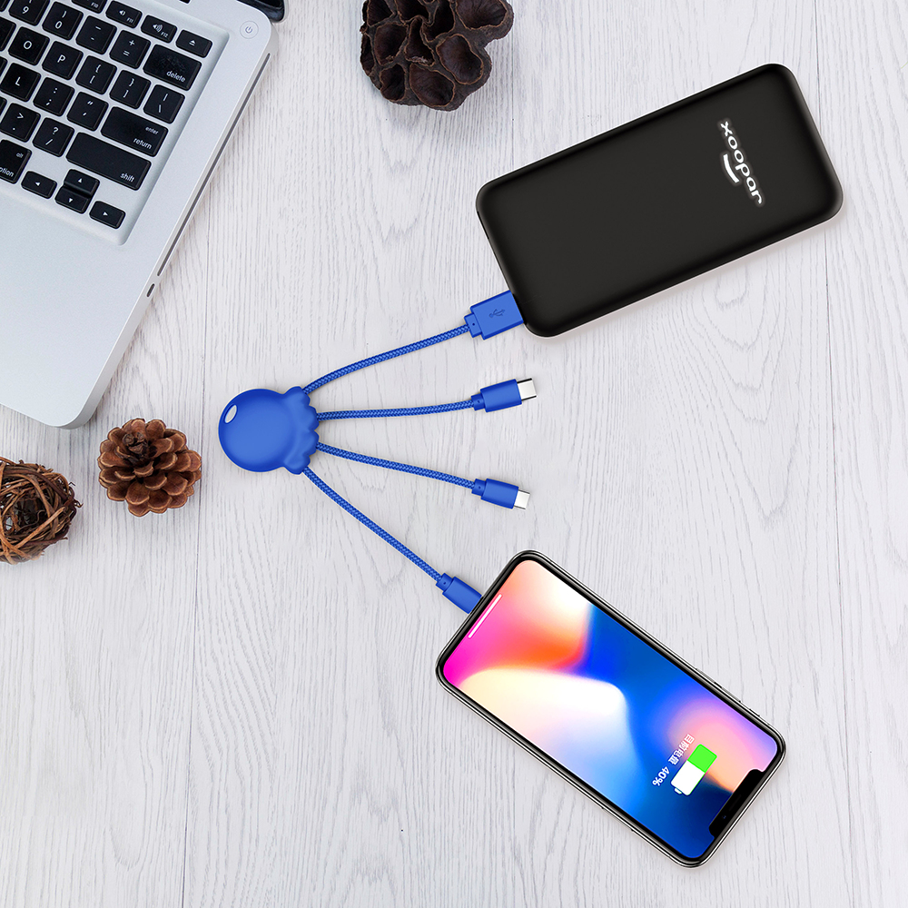 Un power bank nero carica un telefono, collegato da un cavo blu a polpo.