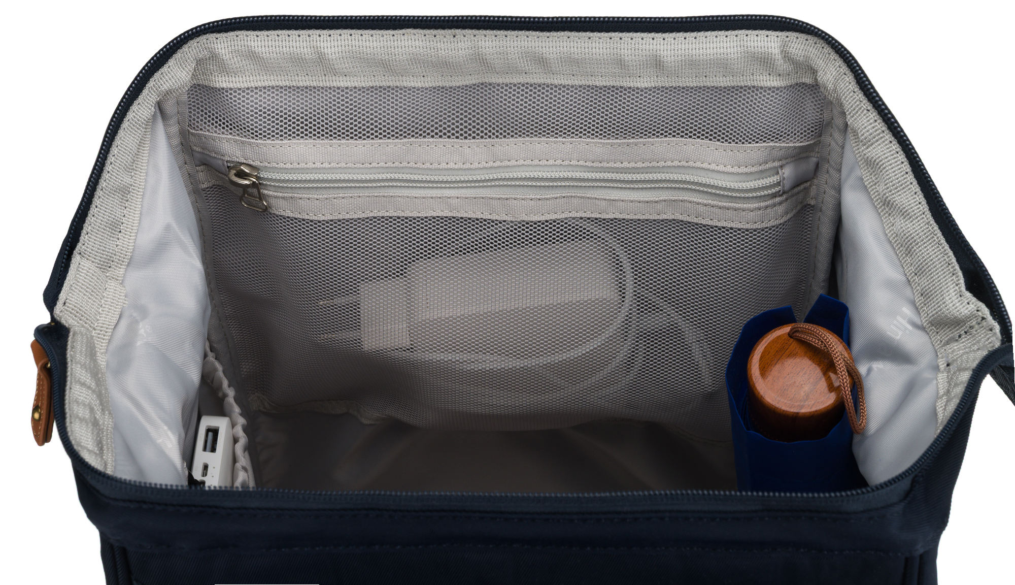 Otwarte wnętrze granatowego plecaka: kieszenie z siatki, ładowarka i przedmiot z drewnianą nakładką.