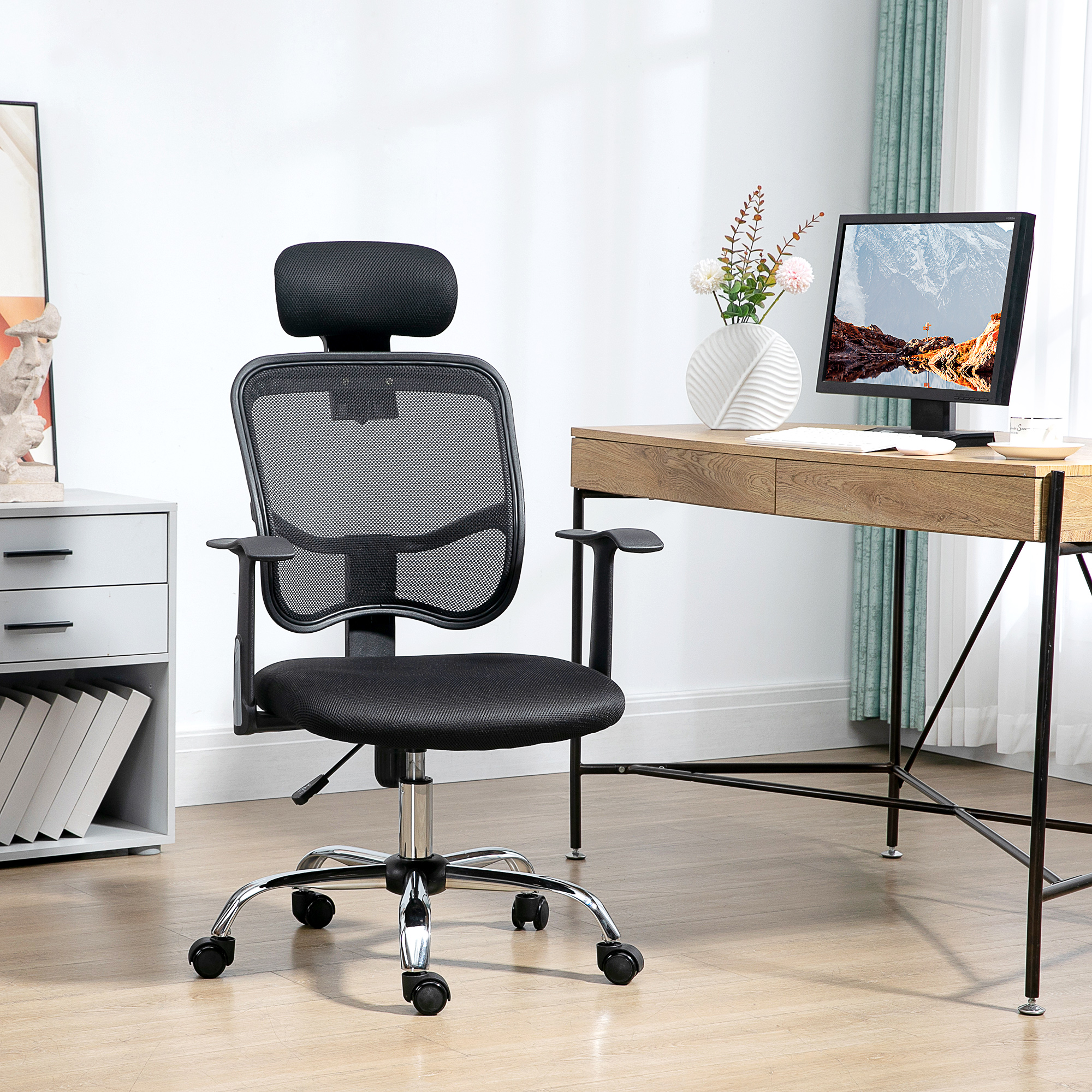 Una sedia da ufficio nera in rete con poggiatesta è di fronte a una scrivania con monitor.