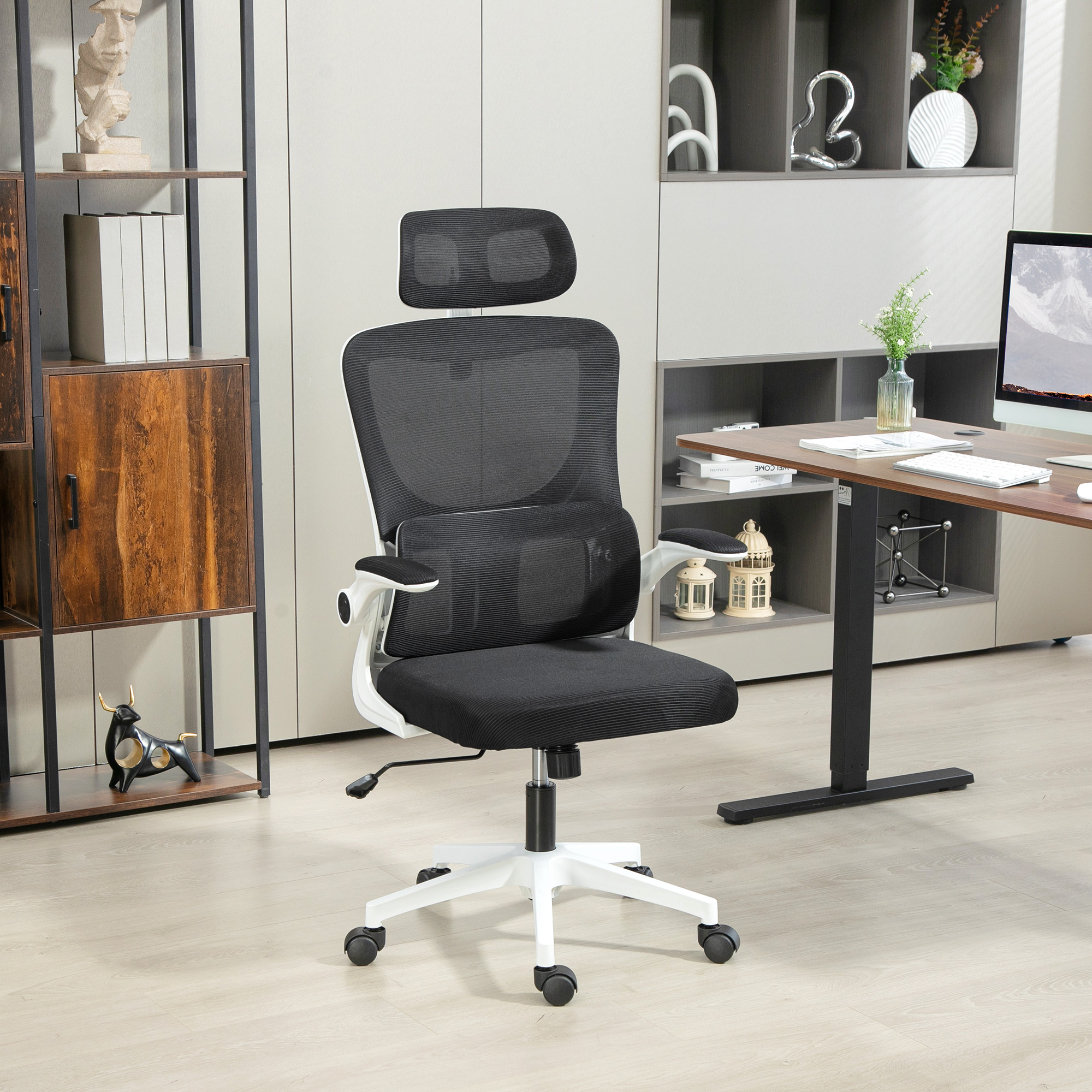Una sedia da ufficio nera con telaio bianco si trova in un ufficio con scaffali e scrivania.