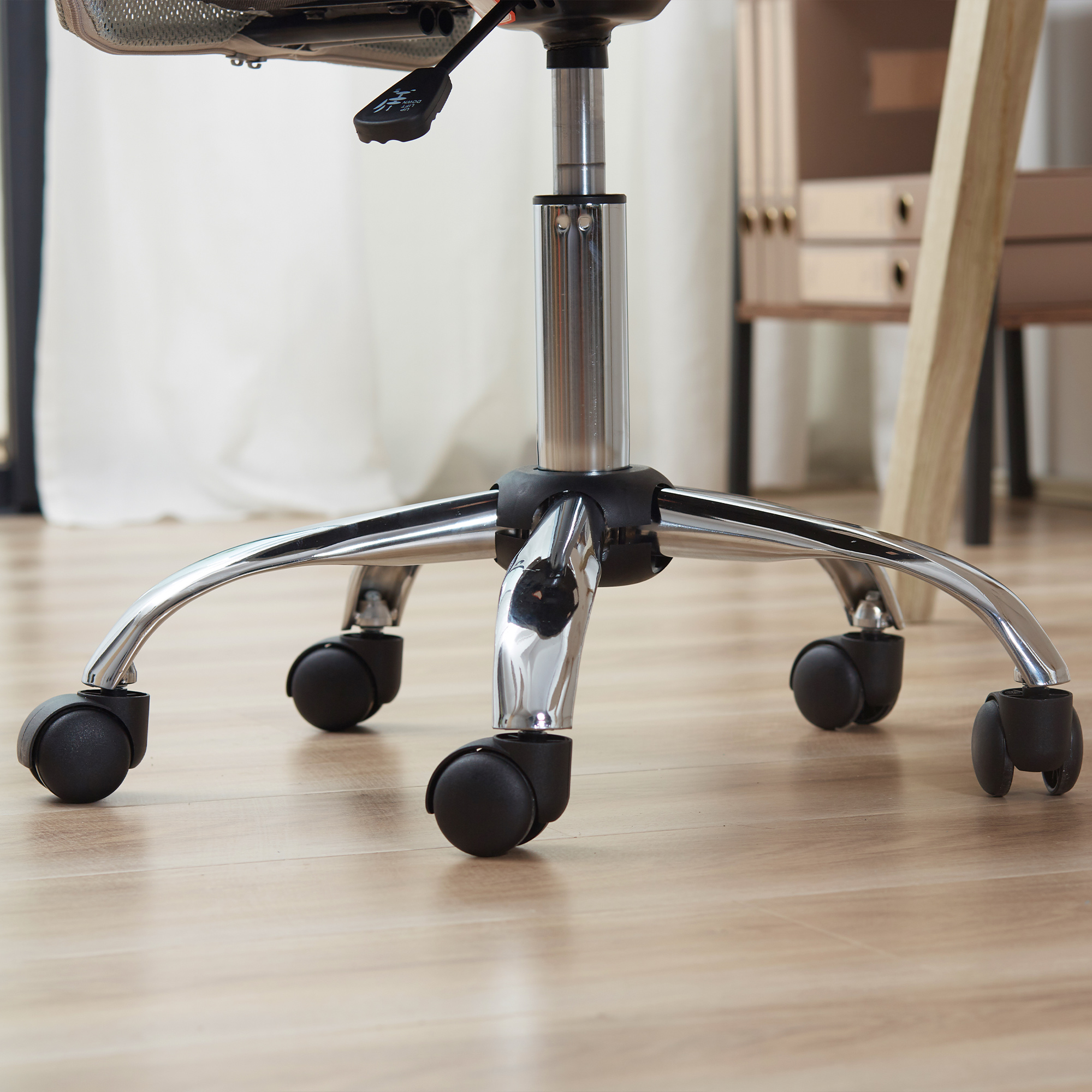 Base sedia ufficio cromata con cinque ruote su pavimento in legno.