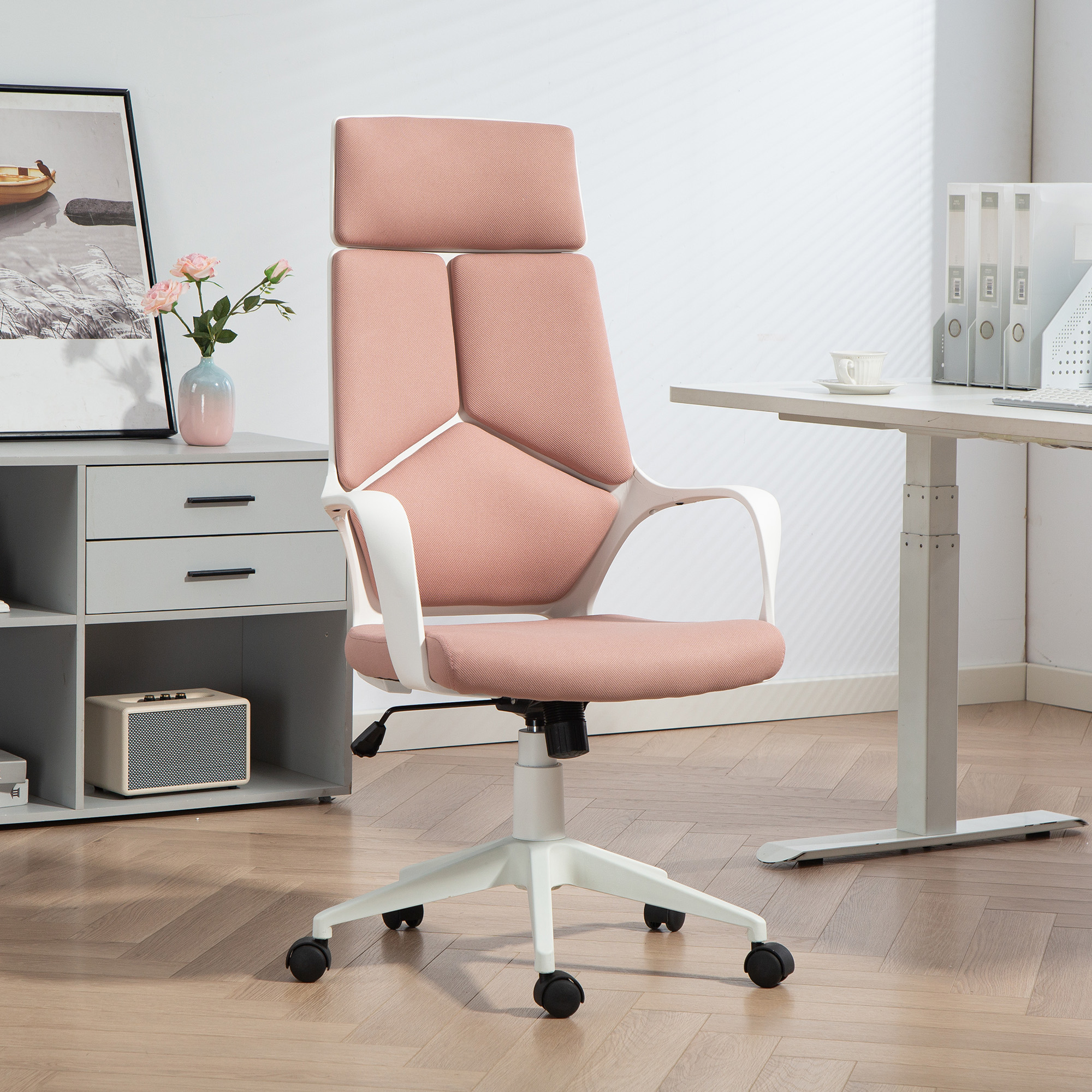 Una sedia da ufficio rosa con telaio bianco si trova su un pavimento in legno accanto a una scrivania.