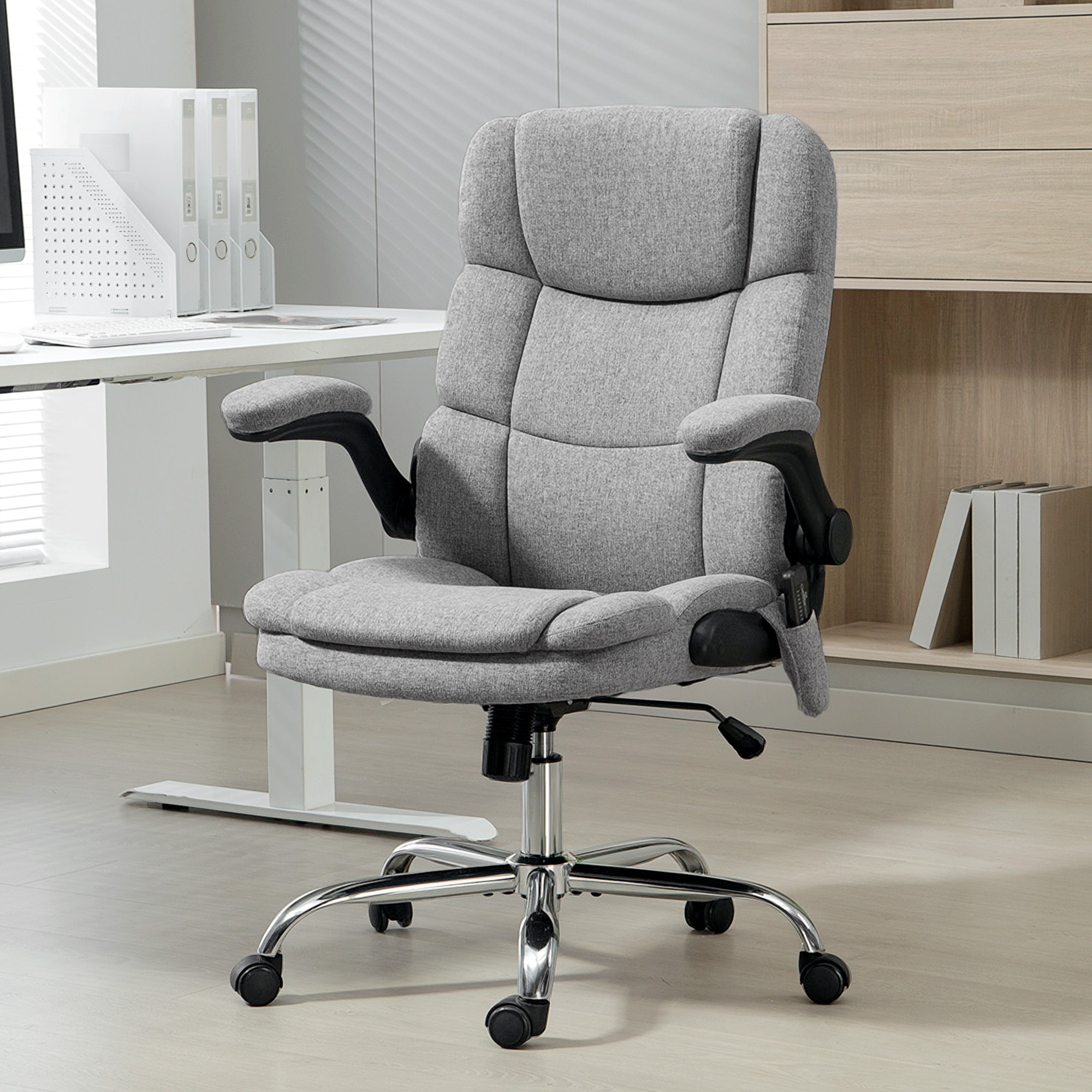 Sedia da ufficio in tessuto grigio con base cromata e ruote su pavimento in legno.