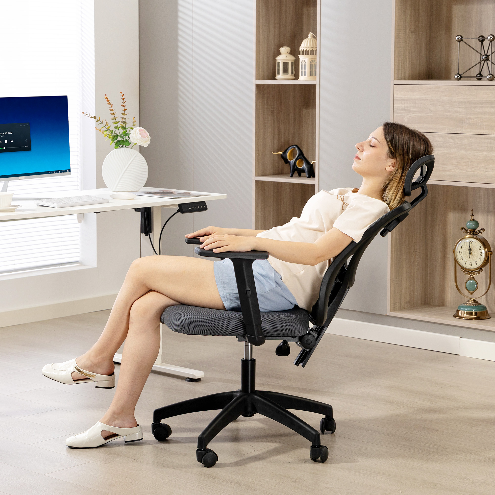 Una donna si riposa su una sedia ergonomica con gli occhi chiusi. Una scrivania è in primo piano.
