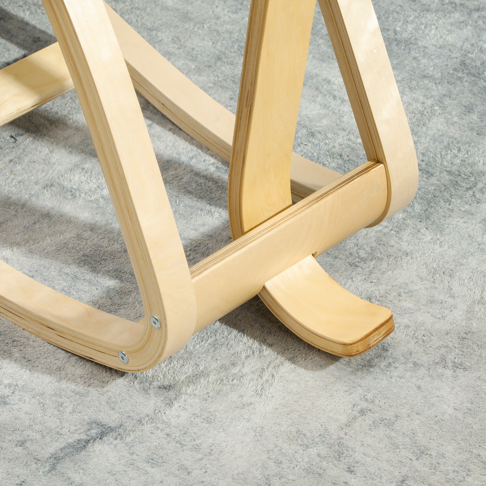 Struttura sedia in legno chiaro su tappeto soffice.