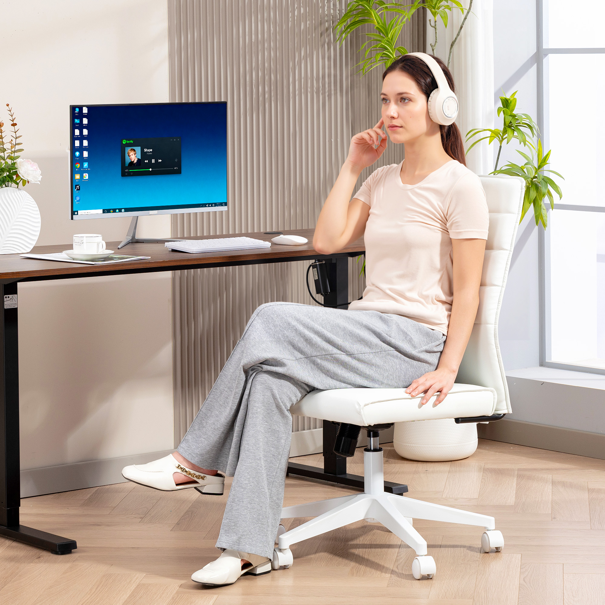 Una donna con cuffie siede a una scrivania, guardando lo schermo di un computer.