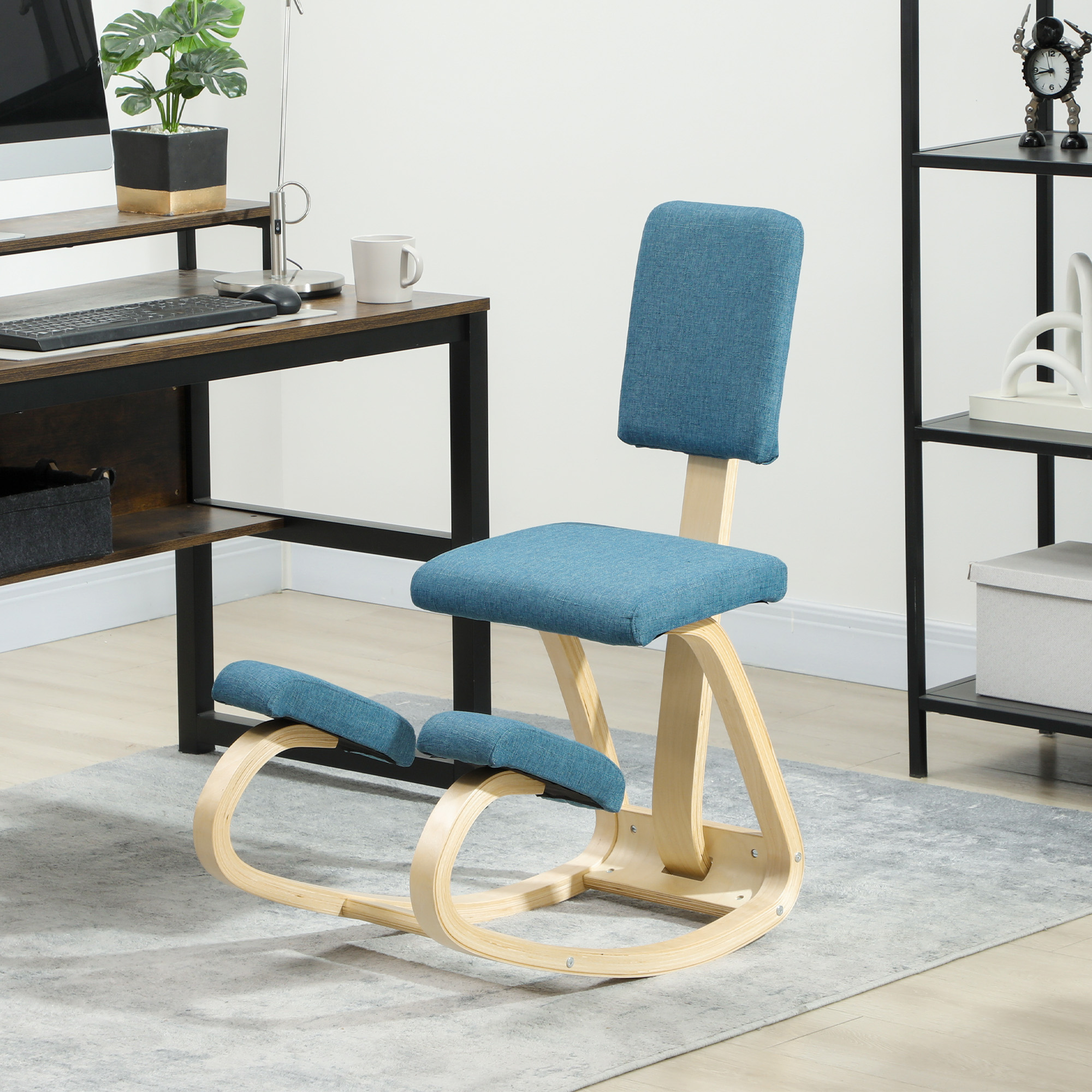 Una sedia inginocchiata blu con telaio in legno siede su un tappeto grigio accanto a una scrivania.