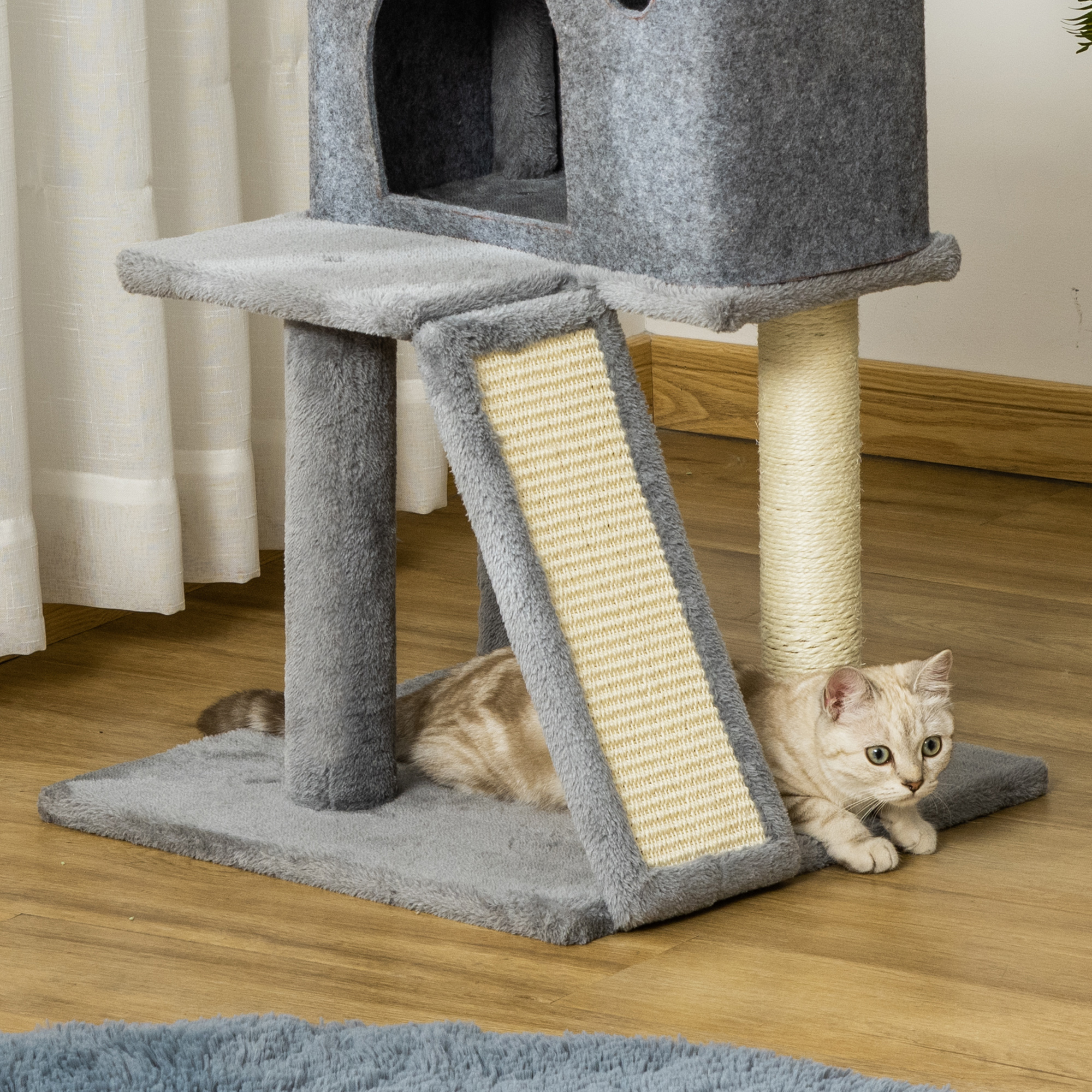 Un gatto è sdraiato sul pavimento accanto a un tiragraffi a più livelli.