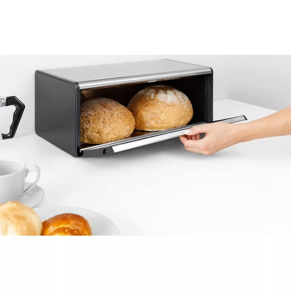 Un portapane nero con coperchio in acciaio inox contiene due pagnotte rotonde.