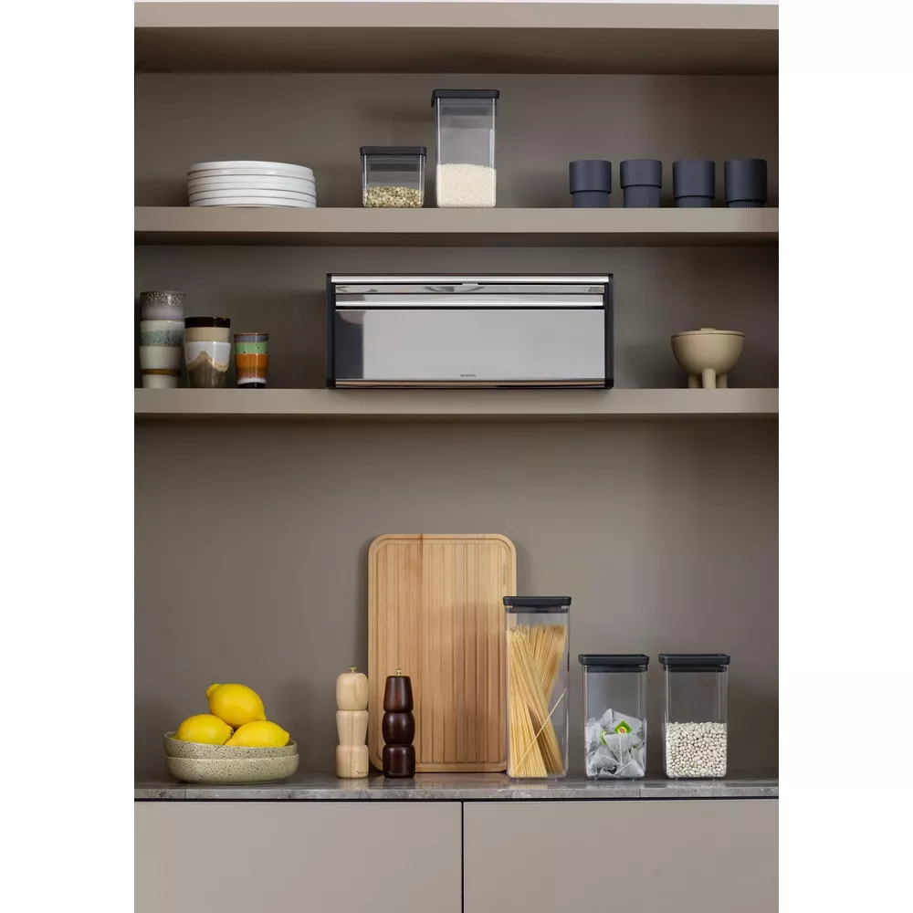 Scaffale da cucina con cibo: limoni, macina spezie, pasta, fagioli, portapane.