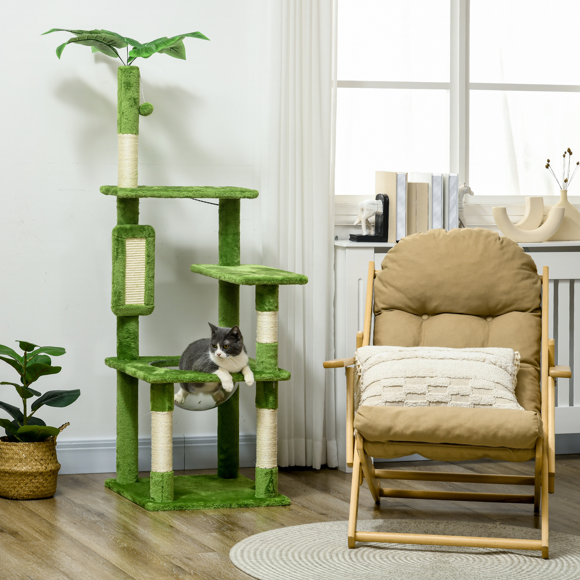 Un gatto riposa su un albero tiragraffi verde con cima frondosa. Una sedia è vicina.