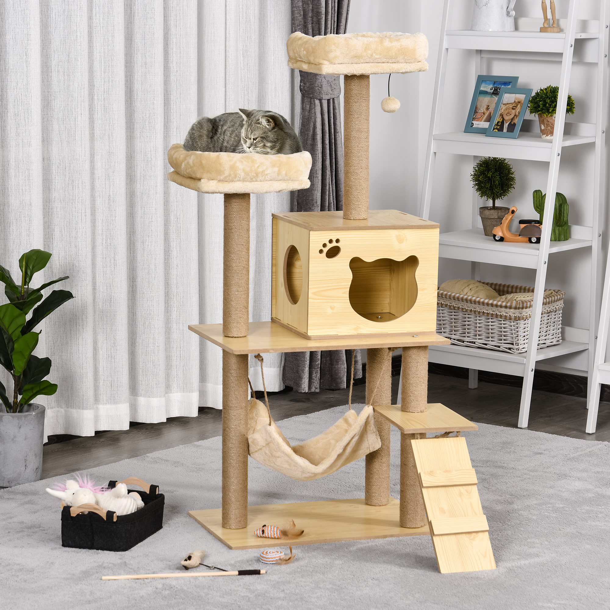 Gatto soriano grigio dorme su un albero per gatti con amaca e giocattoli.