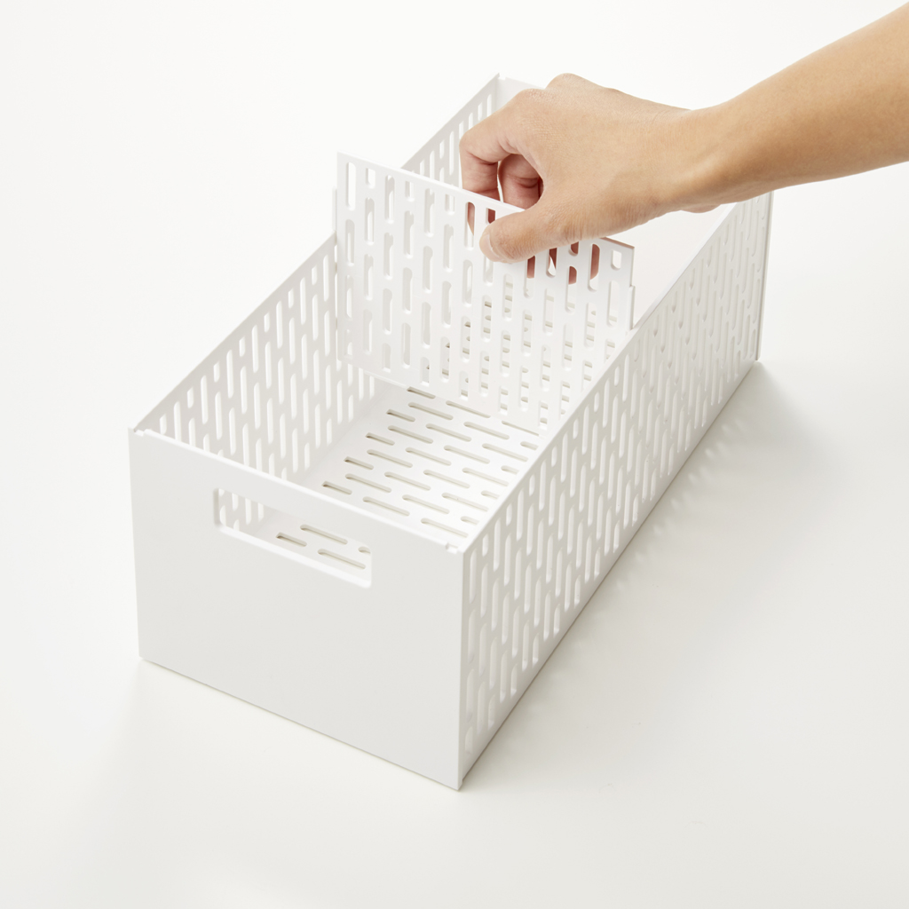 Una mano inserisce un divisorio bianco in un cestino bianco scanalato.