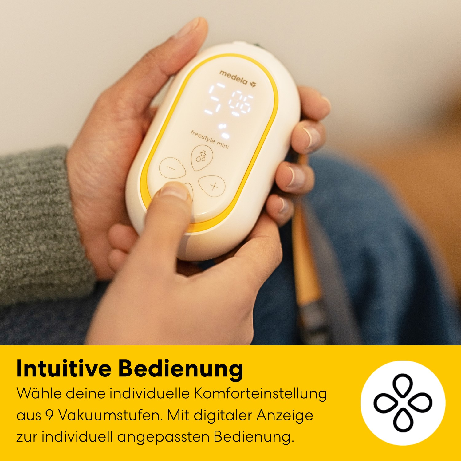 Eine Hand hält ein weißes Medela Freestyle Mini Milchpumpen-Gerät mit digitaler Anzeige.